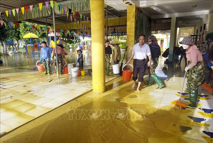 Giáo viên trường tiểu học Tùng Châu (huyện Đức Thọ, Hà Tĩnh) và phụ huynh lau dọn sân trường. Ảnh: Công Tường/TTXVN