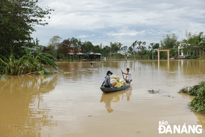 Một số người dân ở xã Hòa Tiến, huyện Hòa Vang phải dùng thuyền để di chuyển từ nhà ra đường ADB 5 vì nhiều đoạn ngập sâu vào ngày 28-9. Ảnh: HOÀNG HIỆP