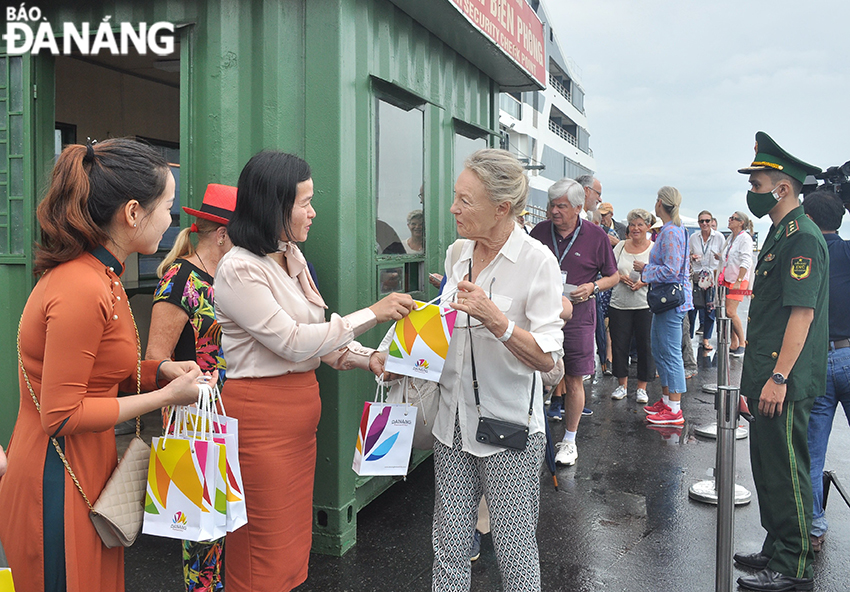 A representative of the Da Nang Tourism Promotion Centre (2nd from left) presenting flowers to welcome guests on the first cruise ship to Da Nang after a long period of disruption due to COVID-19. Photo: THU HA