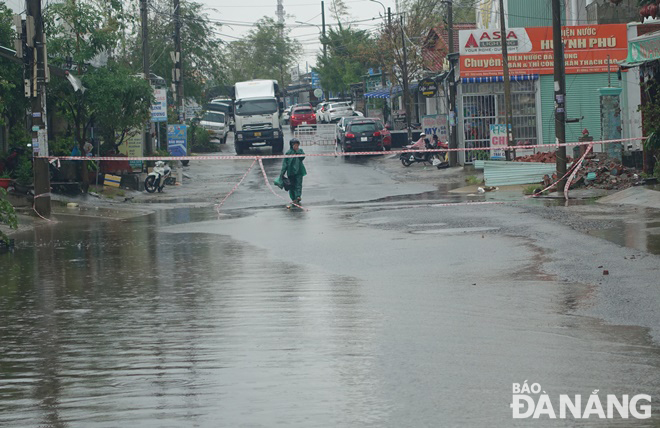 Queues of vehicles in front of a safety barrier waiting to cross National Highway 14G to continue their journey to Quang Nam province’s Dong Giang District as the road is submerged under water.