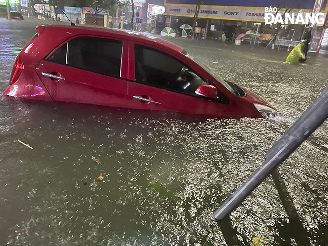 A car is stranded in deep waters in a flooded street