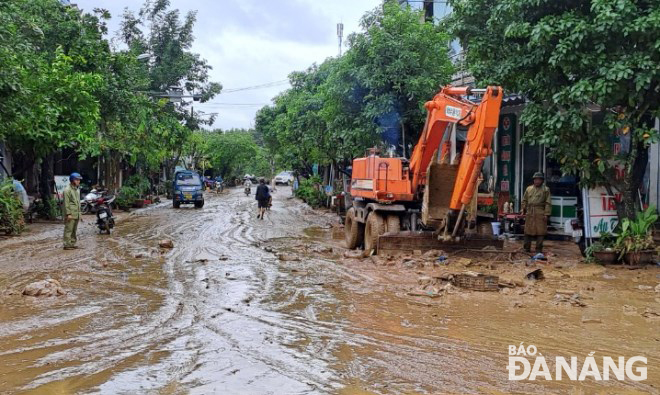 UBND xã Hòa Phú (huyện Hòa Vang) huy động phương tiện cơ giới xúc dọn bùn, đất trên một đoạn đường bị ngập.