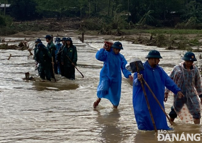Các lực lượng xung kích của xã Hòa Bắc, huyện Hòa Vang di chuyển qua đường tràn để vào một khu vực bị cô lập để giúp nhân dân khắc phục hậu quả lũ lụt. Ảnh: H.H