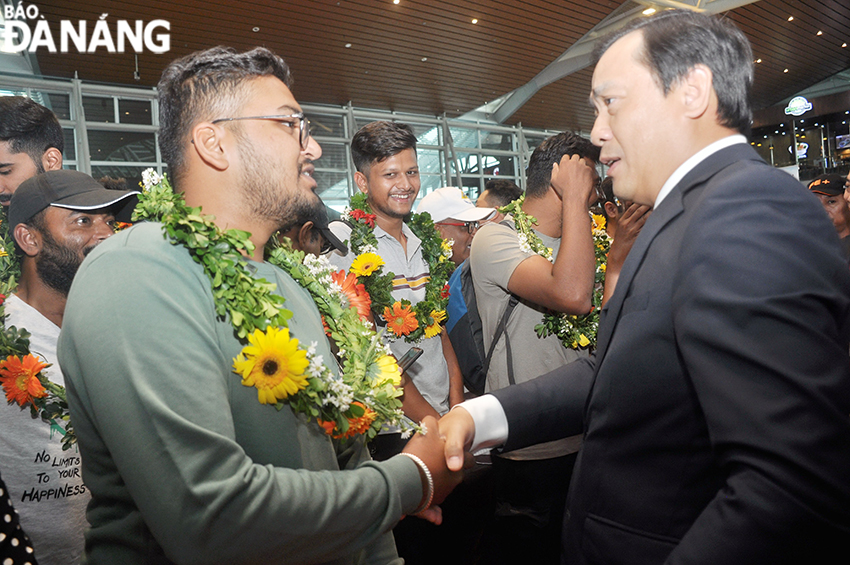 Mr Nguyen Trung Khanh (right) presents flowers to congratulate passengers on the first flight from Da Nang to India. Photo: THU HA