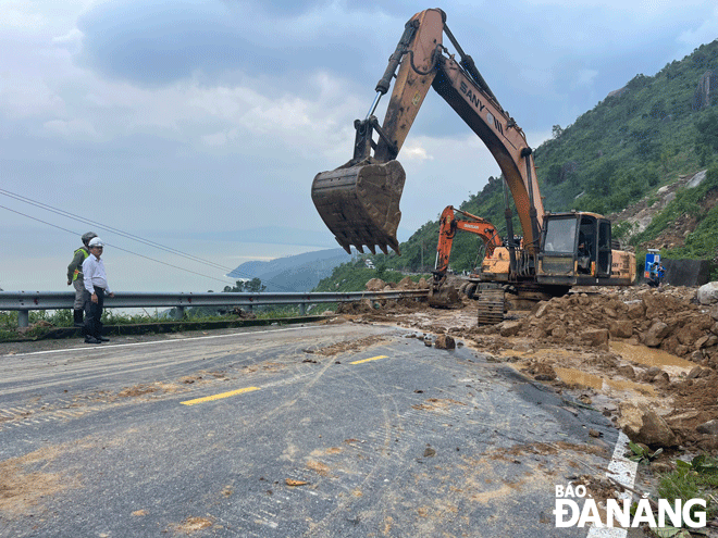 Công nhân thi công san gạt đất đá tràn xuống tuyến đường bộ đèo Hải Vân. Ảnh: TRIỆU TÙNG