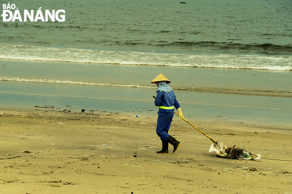 A sanitation worker is diligently collecting garbage to make the beach cleaner and more beautiful.