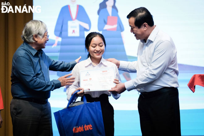 Mr. Phan Viet Cuong, the Secretary of the Quang Nam Provincial Party Committee (right), and Mr. Pham Phu Tam, the Chairman of the Quang Nam- Da Nang Club to give strength to students to go to school and a scholarship recipient . Photo: NGOC HA.