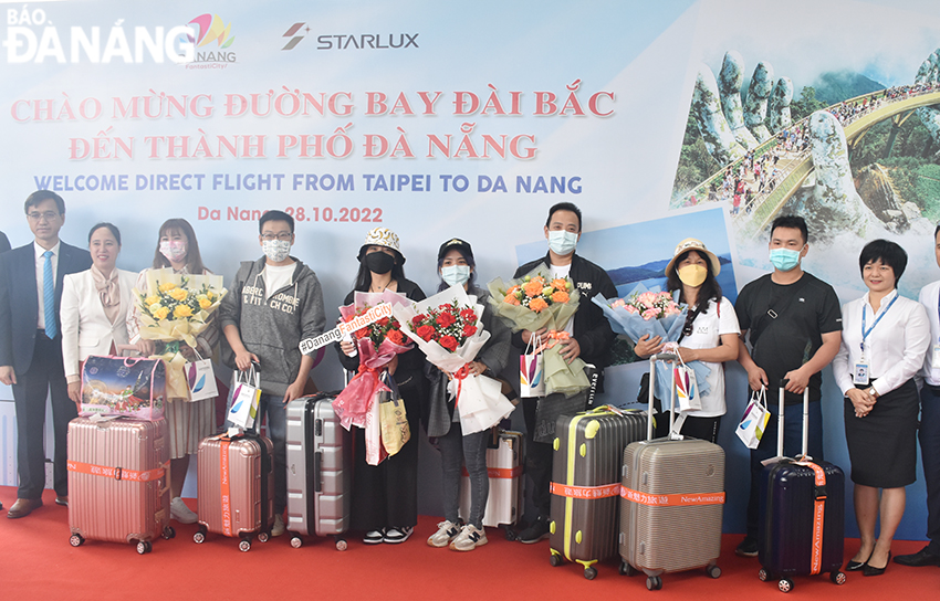 Đại diện Trung tâm Xúc tiến du lịch (thứ 2 từ trái sang) tặng hoa chúc mừng những vị khách trên chuyến bay đầu tiên đến Đà Nẵng. Ảnh: THU HÀ