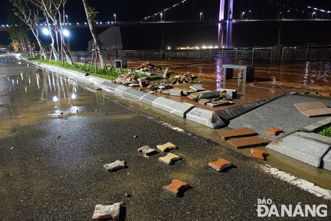 High waves peeled off sidewalk tiles on riverside Nhu Nguyet Street and pushed them down on the road surface. Photo: HOANG HIEP