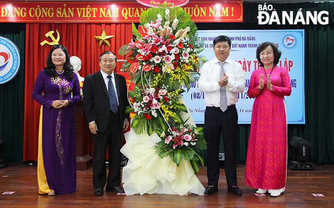 Deputy Secretary Luong Nguyen Minh Triet (second, right) and Vice Chairwoman Ngo Thi Kim Yen (first, right) presenting flowers to congratulate the 20th birrthday of the Da Nang Association for Supporting Poor and Disadvantaged Women and Children. 