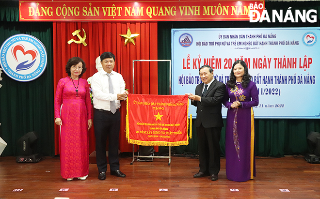 Deputy Secretary Luong Nguyen Minh Triet (second, left) and Vice Chairwoman Ngo Thi Kim Yen (first, left) presenting the emulation flag of the municipal People's Committee to the Da Nang Association for Supporting Poor and Disadvantaged Women and Children