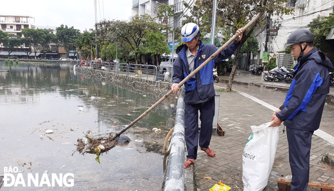 Công nhân Công ty Thoát nước và Xử lý nước thải Đà Nẵng thu gom rác chảy vào hồ Vĩnh Trung (quận Thanh Khê) sau một trận mưa lớn để bảo đảm môi trường, cảnh quan hồ. Ảnh: HOÀNG HIỆP