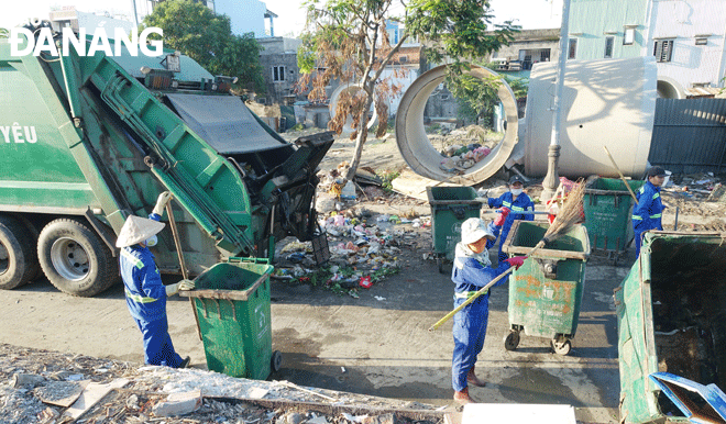Các công nhân tổng dọn rác tại điểm tập kết rác trên đường Nguyễn Huy Chương (quận Sơn Trà).  Ảnh: HOÀNG HIỆP
