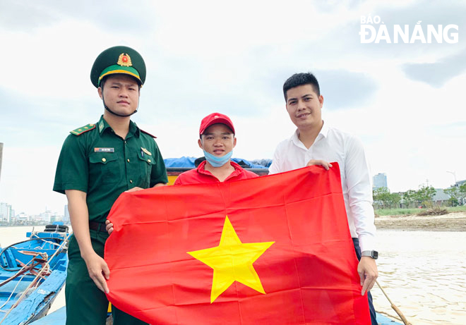 Representatives of the Da Nang Border Guard at the Tien Sa Port border gate station (left) and Thuan Phuoc Ward authorities (right) present the national flag to a fisherman. Photo courtesy of Tien Sa Port border guard station.