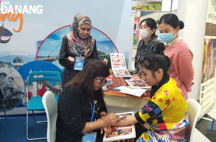 Residents and visitors experience hand-painted decorations at the Malaysian pavilion. Photo: THU HA