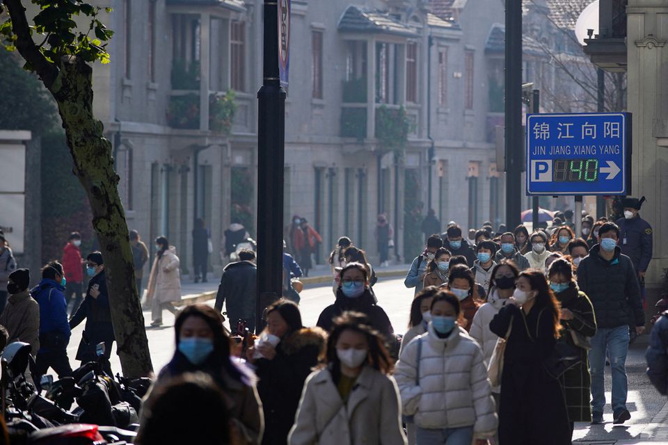 Người dân đeo khẩu trang đi trên đường phố Thượng Hải, Trung Quốc, ngày 13-12. Ảnh: Reuters