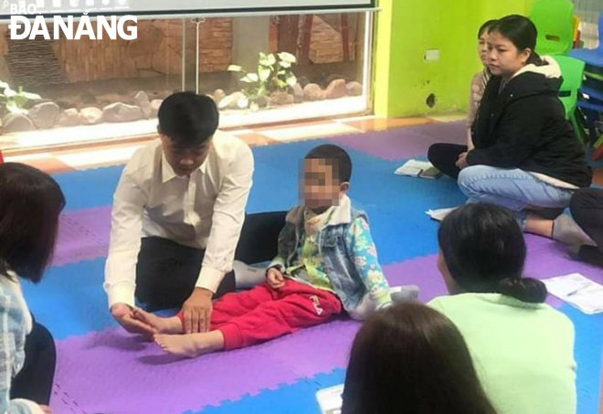 Teacher Nguyen Xuan Viet is helping an autistic child to do physical exercise. Photo: THAO NGUYEN