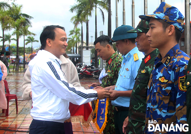 Head of the municipal Party Committee’s Organisation Board Nguyen Dinh Vinh gives souvenir flags to representatives from the groups of participating runners