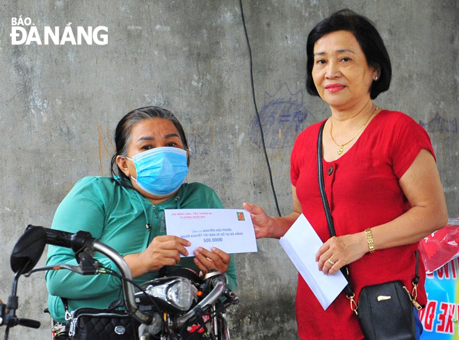 Small traders from the Han Market give Tet gifts to disabled people selling lottery tickets in the city. Photo: T.Y