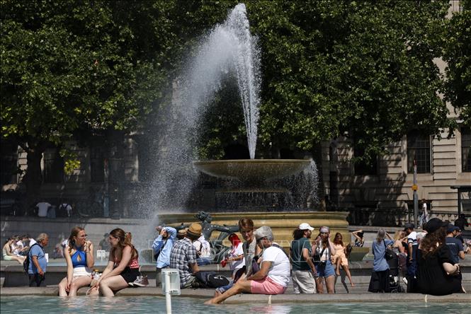 Người dân tránh nóng bên đài phun nước tại Quảng trường Trafalgar ở thủ đô London, Anh, ngày 17/6/2022. Ảnh: AFP/TTXVN