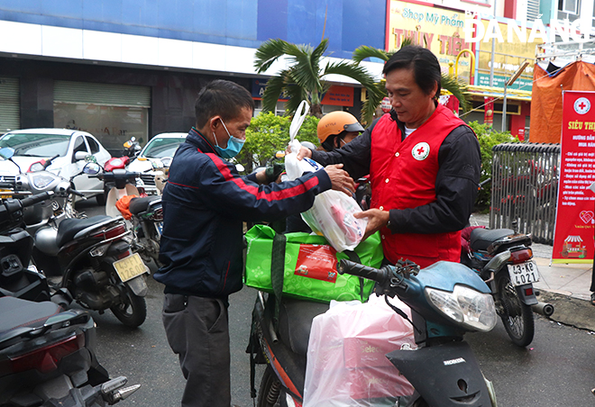 Cán bộ Hội Chữ thập đỏ thành phố hỗ trợ người dân đưa đồ về nhà. Ảnh: X.D