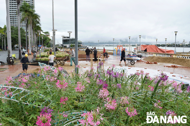 Workers are installing floral decorations in front of the T-shaped bridge on Bach Dang Street