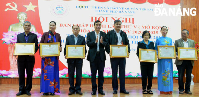 Da Nang People's Committee Chairman Le Trung Chinh presenting Certificates of Merit to 7 individuals in recognition of their outstanding achievements in implementing the ‘Helping poor households overcome difficulties and protect children's rights’ emulation movement 2022. Photo: PHAN CHUNG.