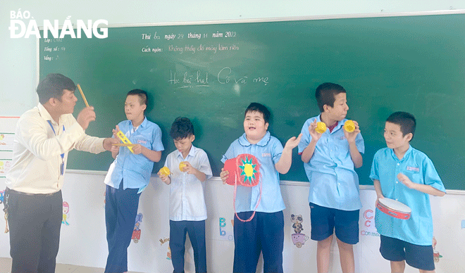 Teacher Le Quang Hai (right) instructs children with disabilities how to use each instrument created by himself. Photo: T.P