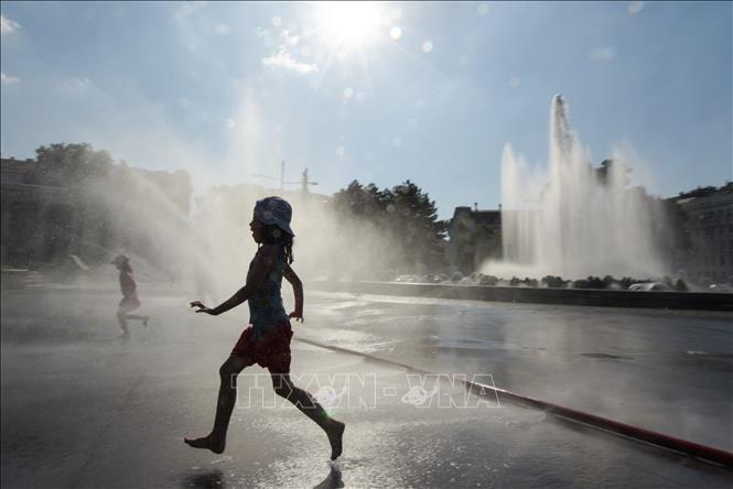 Trẻ em chơi đùa tại khu vực đài phun nước ở quảng trường Schwarzenberg, Áo để tránh nắng nóng với nhiệt độ lên tới 36 độ C, ngày 26-6-2019. Ảnh: THX/TTXVN