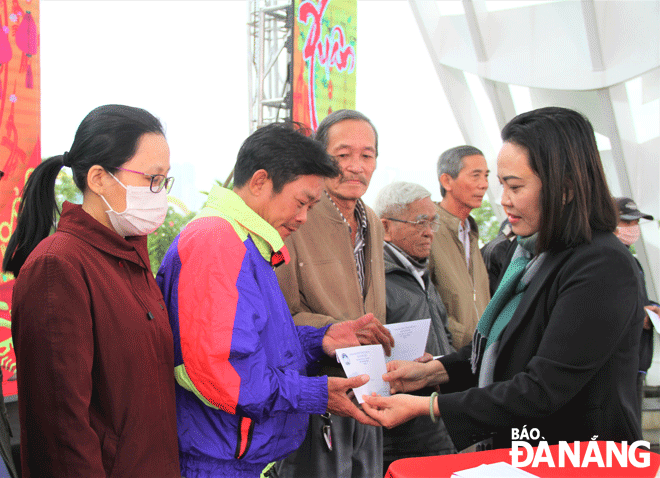 Deputy Director of the Municipal Department of Labor, War Invalids and Social Affairs Nguyen Thi Thu Huong (first, right) presenting Tet cash gifts to the poor in Hai Chau District. Photo: LAM PHUONG