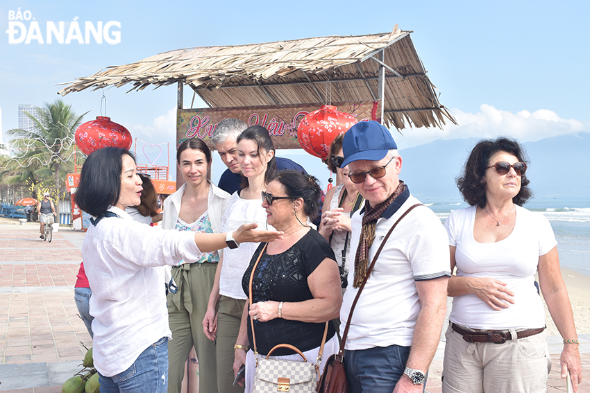 Một đoàn khách Pháp ghé check-in tại biển Đà Nẵng thích thú khi thấy các hoạt động làm bánh tết được tổ chức tại đây. Ảnh: THU HÀ.