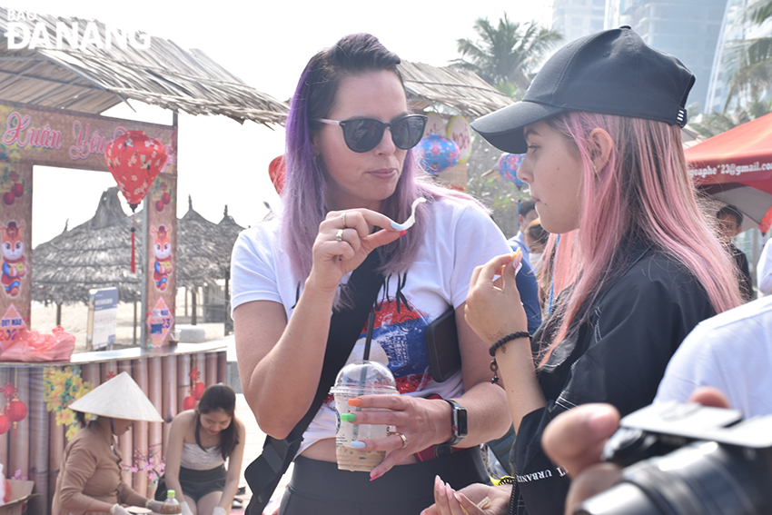 The family of Danielle Rothwell, coming to Da Nang for the firts time, are trying free cakes at the programme. Photo: THU HA