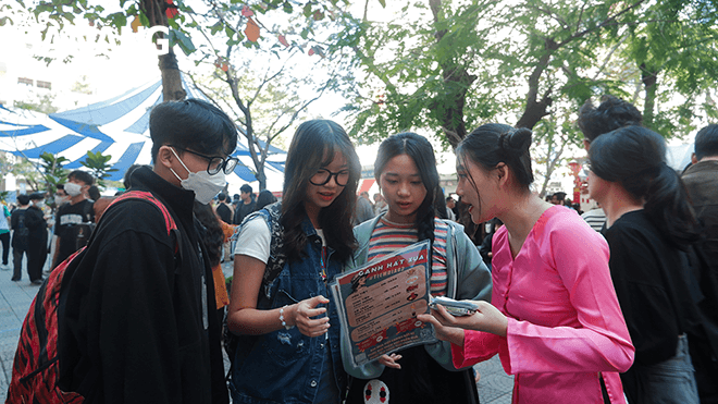 A member of the booth 'Ganh Hat Xua' (first, right) of class 12/2 invites diners.