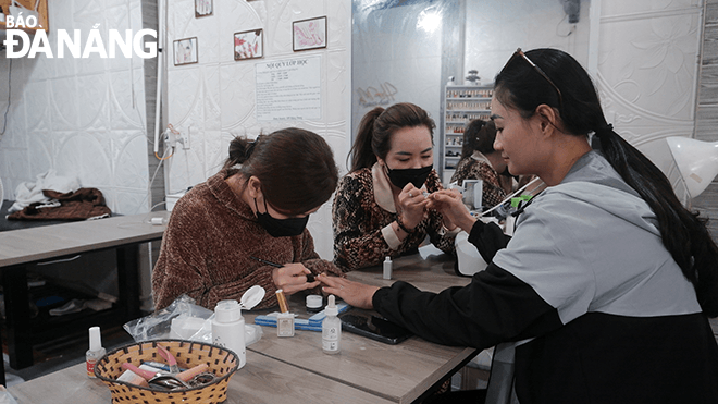 Le Thi Kim Anh (middle) and staff rush to complete the nails for their guest. Photo: T.D