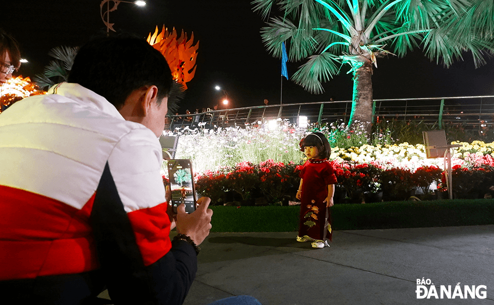 Children who get dressed in Tet costumes were saved memories at the flower garden by their parents. Photo: QUOC CUONG