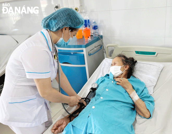 A nurse at the Da Nang General Hospital taking care of a female stroke patient. Photo: PHAN CHUNG