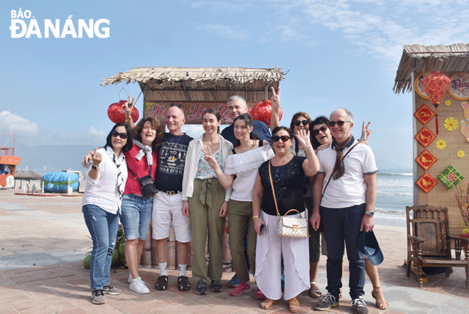 The city's tourism industry needs to soon add products to attract more international visitors to Da Nang. IN THE PHOTO: A group of French tourists took souvenir photos at Da Nang beach. Photo: THU HA