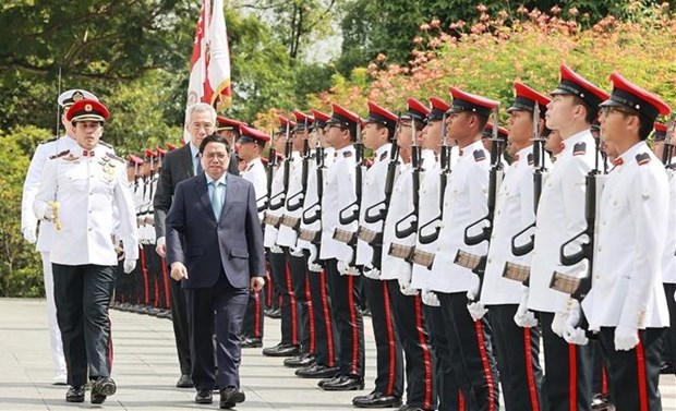 Singaporean Prime Minister Lee Hsien Loong hosts the official welcome ceremony for Prime Minister Pham Minh Chinh (front). (Photo: VNA)