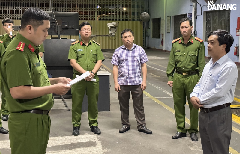 Đại diện lãnh đạo Trung tâm Đăng kiểm xe cơ giới Đà Nẵng (bìa phải) nghe Cơ quan Cảnh sát điều tra, Công an thành phố tống đạt quyết định khám xét khẩn cấp.