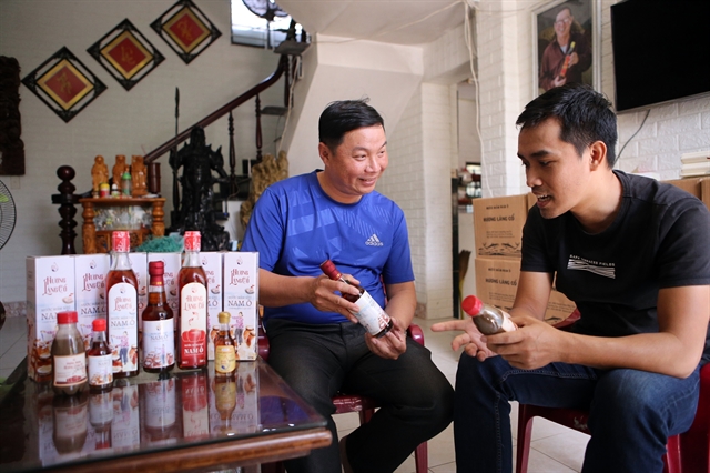 LIKE FATHER, LIKE SON: Bùi Văn Phong (left) is the fourth generation of a family making fish sauce in Nam Ô Village in Liên Chiểu District of Đà Nẵng. The family brand is a four-star product of agro-tourism development in the city. VNS Photo Tran Le Lam