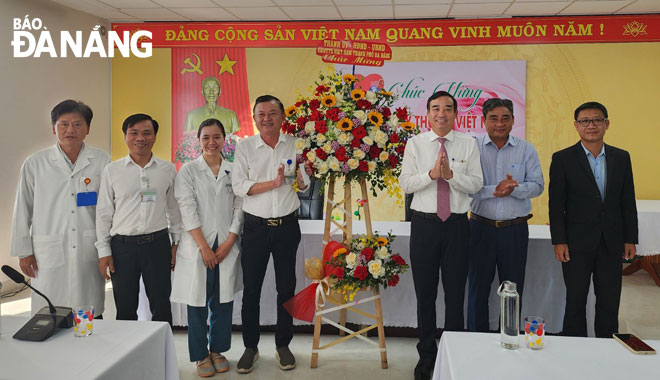 Municipal People's Committee Chairman Le Trung Chinh (3rd, right) presented flowers to congratulate the staff of the Son Tra District Medical Center. Photo: PHAN CHUNG