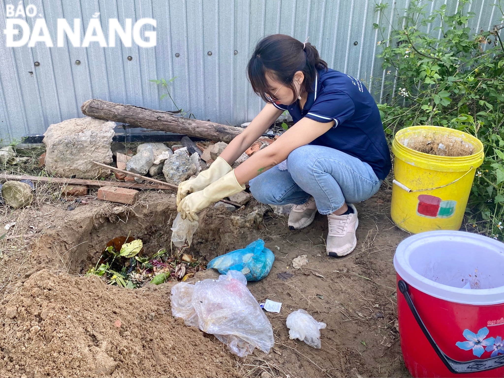 Sau khi phân loại rác, chị Vũ Hồng Thanh (đồng sáng lập dự án cộng đồng không rác tại Đà Nẵng) cho những rác thải hữu cơ xuống hố để tiến hành ủ phân Compost. Ảnh: N.QUANG