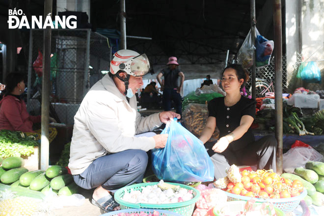 Ông Võ Văn Đức đi chợ Hòa Khánh nhận phần rau củ do chị Phan Thị Thanh hỗ trợ. Ảnh: T.Y