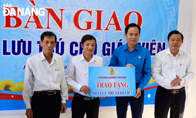 Chairman of the municipal Confederation of Labour Nguyen Duy Minh (second, right) presenting a symbolic board of handover to a representative of Hoa Bac Commune's leaders. Photo: T.PHUONG