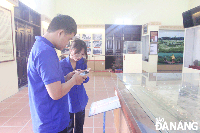 Youth Union member Tran Quoc Chi Hieu (left) uses a smartphone and scans a QR code to find out information about the revolutionary base B1 Hong Phuoc located in Lien Chieu District, Da Nang. Photo: N.Q