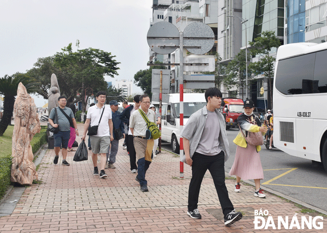 Da Nang-based travel agencies are adding products to serve tourists. IN THE PHOTO: Asian tourists are seen walking on Bach Dang Street. Photo: NHAT HA