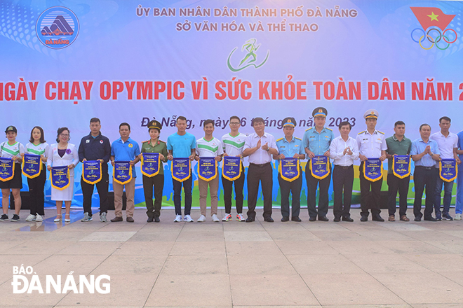 Leaders of the municipal Department of Culture and Sports and members of the Organising Committee presenting souvenir flags to units and localities participating in the Olympic Run Day for Public Health 2023