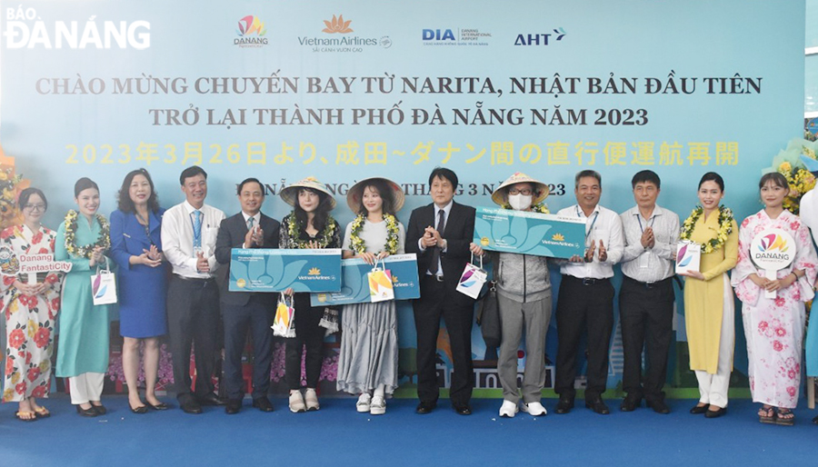 Consul General of Japan in Da Nang Yakabe Yoshinori (6th, right), Deputy Director of the municipal Department of Tourism Nguyen Xuan Binh (5th, left) and related units give gifts to the first guests from Japan on the Da Nang - Narita flight. Photo: THU HA