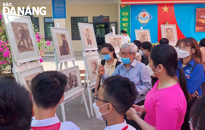 Painter and sculptor Pham Hong (middle) talked with pupils of the Nguyen Van Linh Junior High School at the exhibition themed 'Sketches of the Zone 5 Battlefield' in 2022. Photo: D.H.L