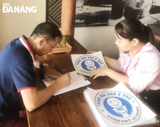 A public servant from the Son Tra District administration’s (right) guides the owner of a service establishment to participate in the ‘Comfort as home’ model. Photo: NHAT HA